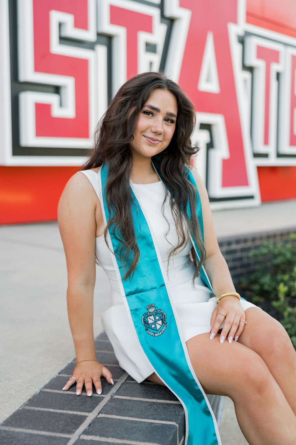 arkansas state graduating senior poses in front of college sign